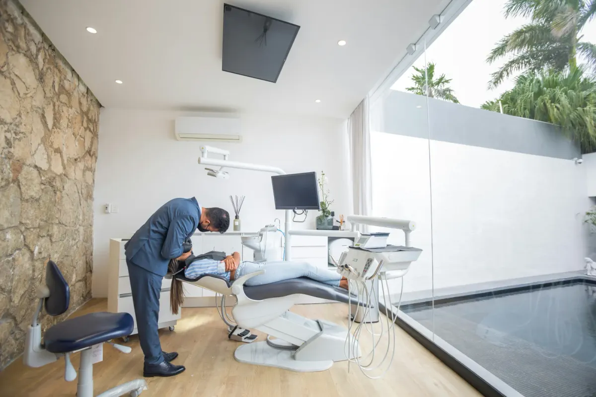 A dentist treating a patient in a bright modern dental clinic with a natural stone feature wall and daylight