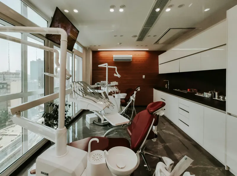 A sleek modern dental treatment suite with a contemporary chair and a floor-to-ceiling window