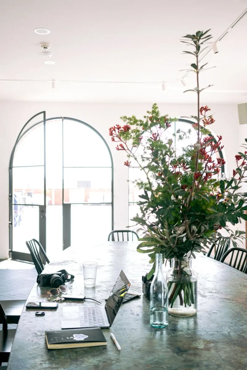 A bright creative workspace with native florals and a laptop in natural light