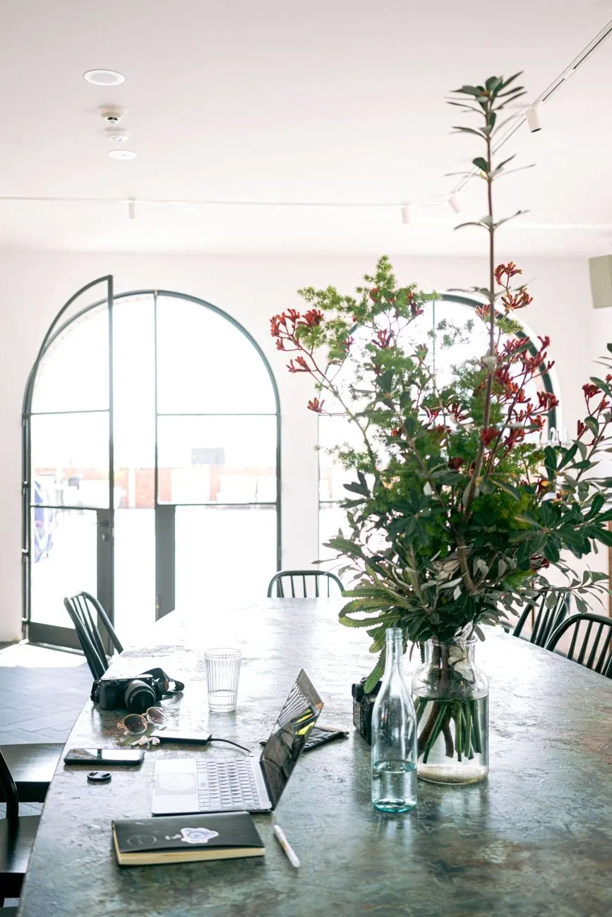 A bright creative workspace with native florals and a laptop in natural light