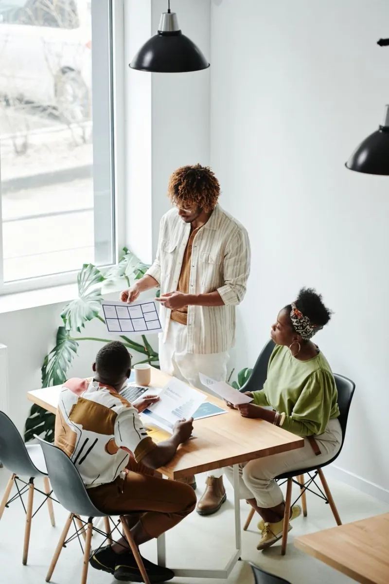 A marketing team reviewing reports around a table in a plant-filled office