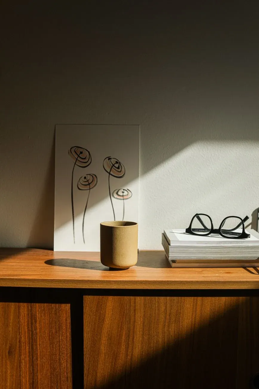 A minimal sideboard with a ceramic vase and a framed art print