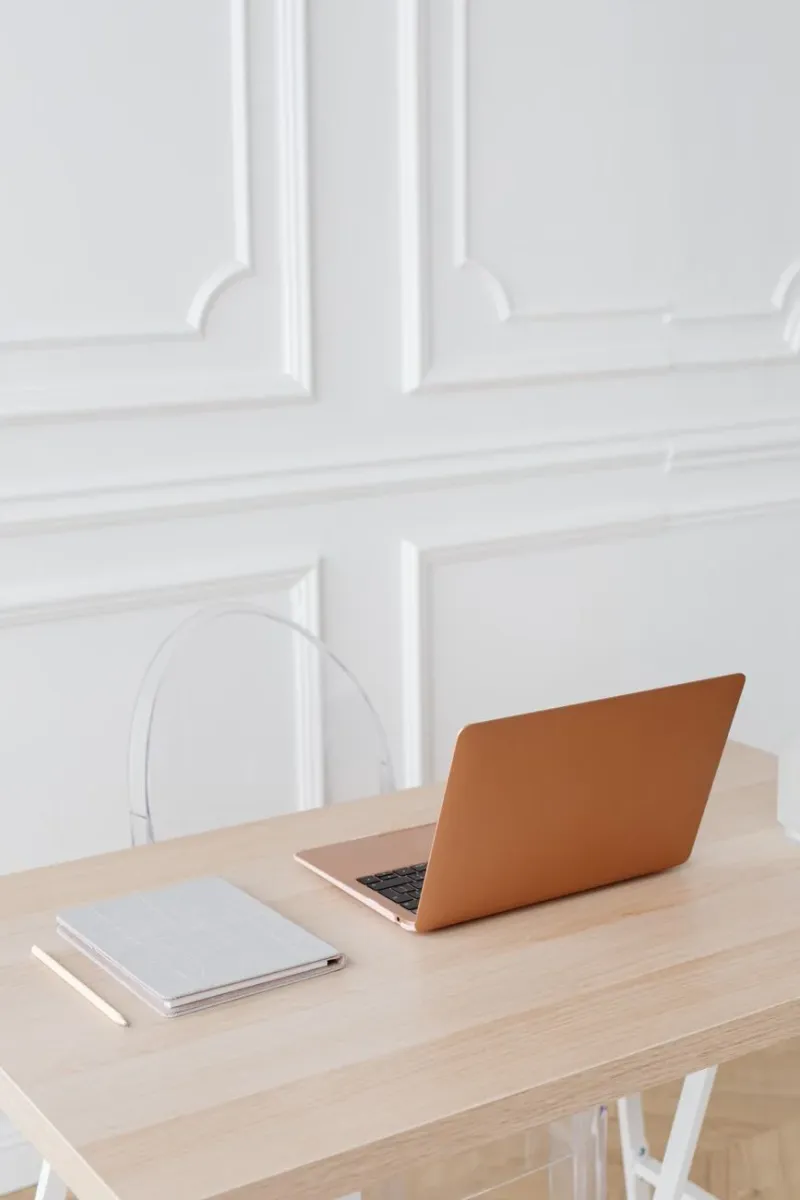 A warm wooden desk with a laptop against an elegant panelled wall
