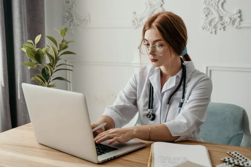 A practice manager and a marketing consultant reviewing search results on a laptop at a reception desk in a bright modern medical clinic