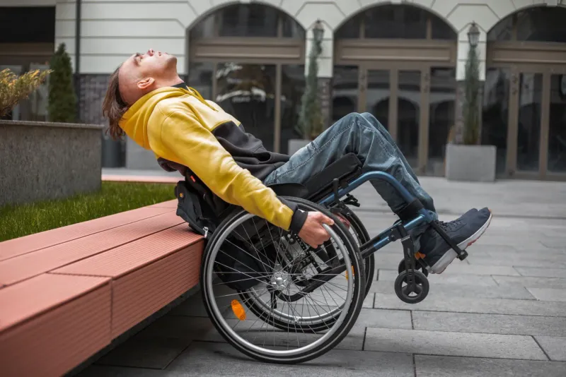 A confident young wheelchair user relaxing outdoors in front of a modern building