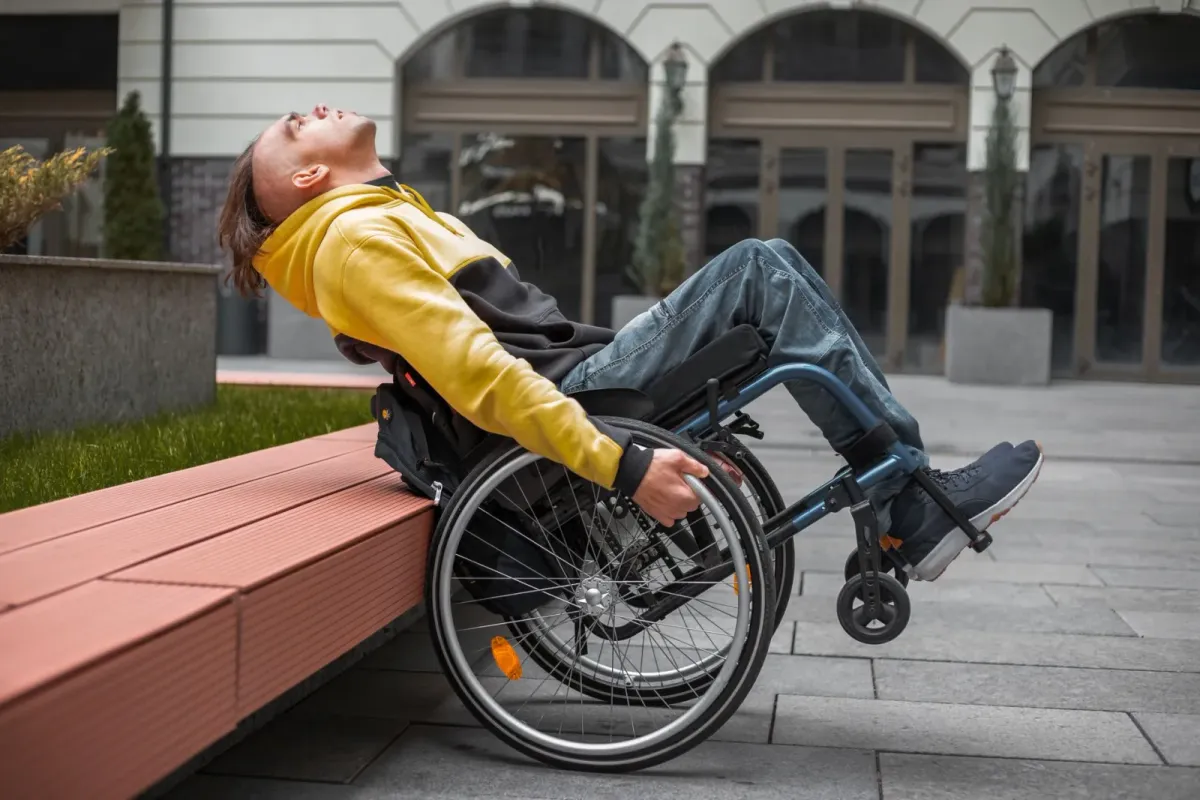 A confident young wheelchair user relaxing outdoors in front of a modern building