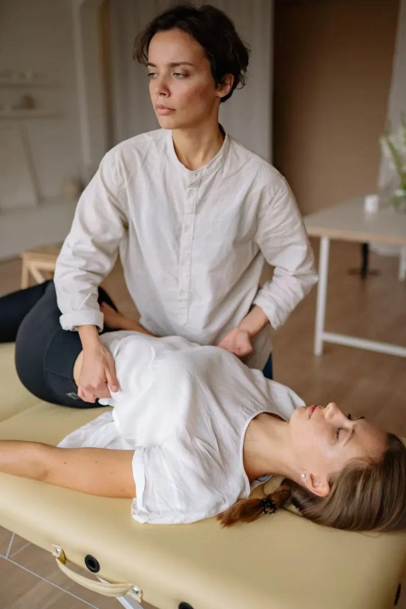 A practitioner performing a hands-on spinal treatment in a warm, naturally lit clinic