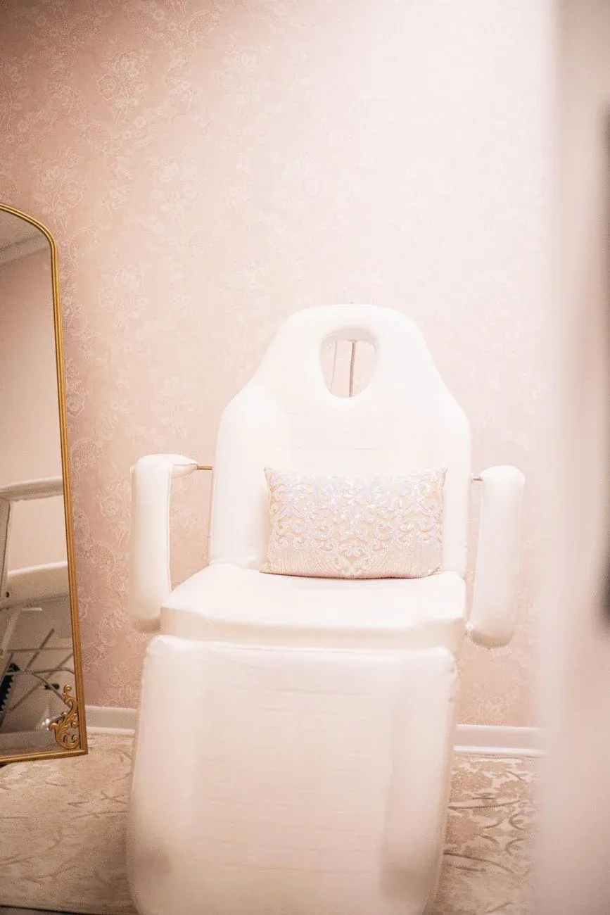 An elegant aesthetic treatment chair in a soft pink minimal room