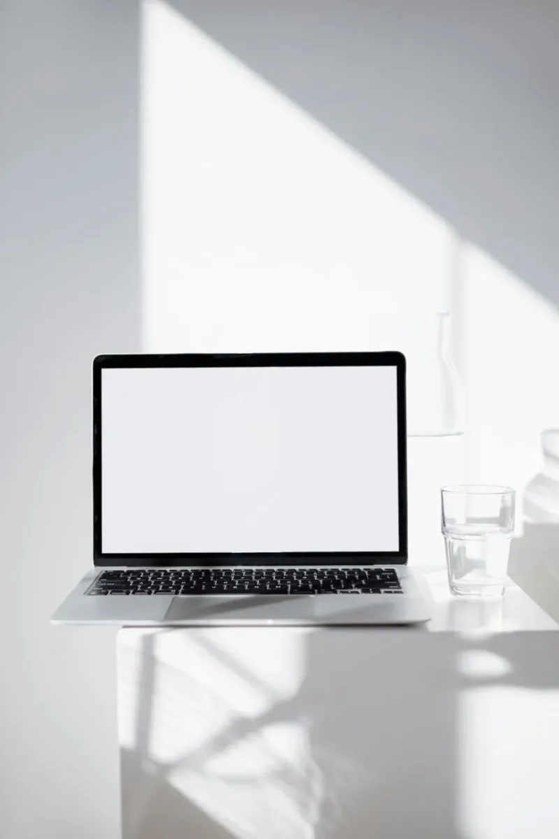 A minimalist laptop on a white desk in soft natural light