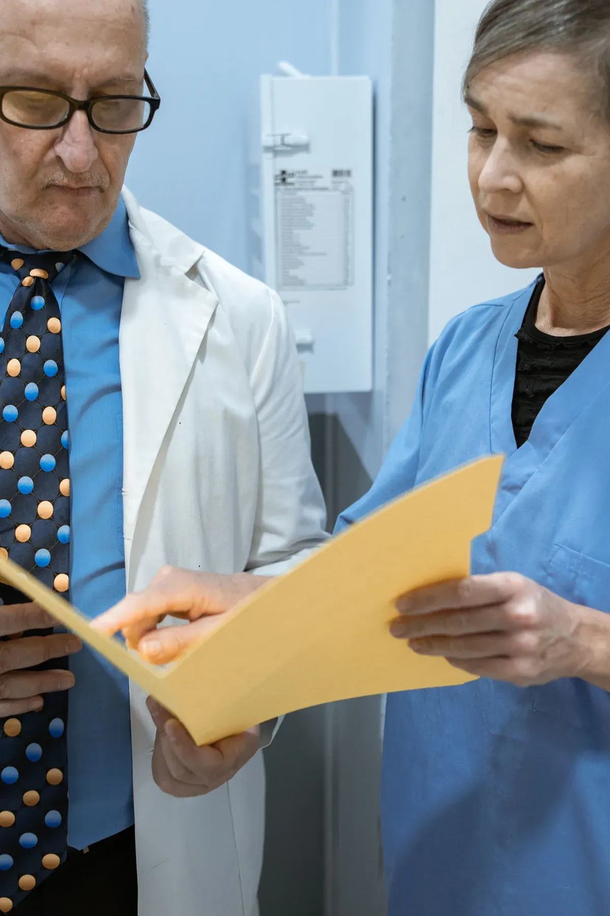 Australian allied health professional reviewing pricing documents with a colleague in a bright modern clinic office