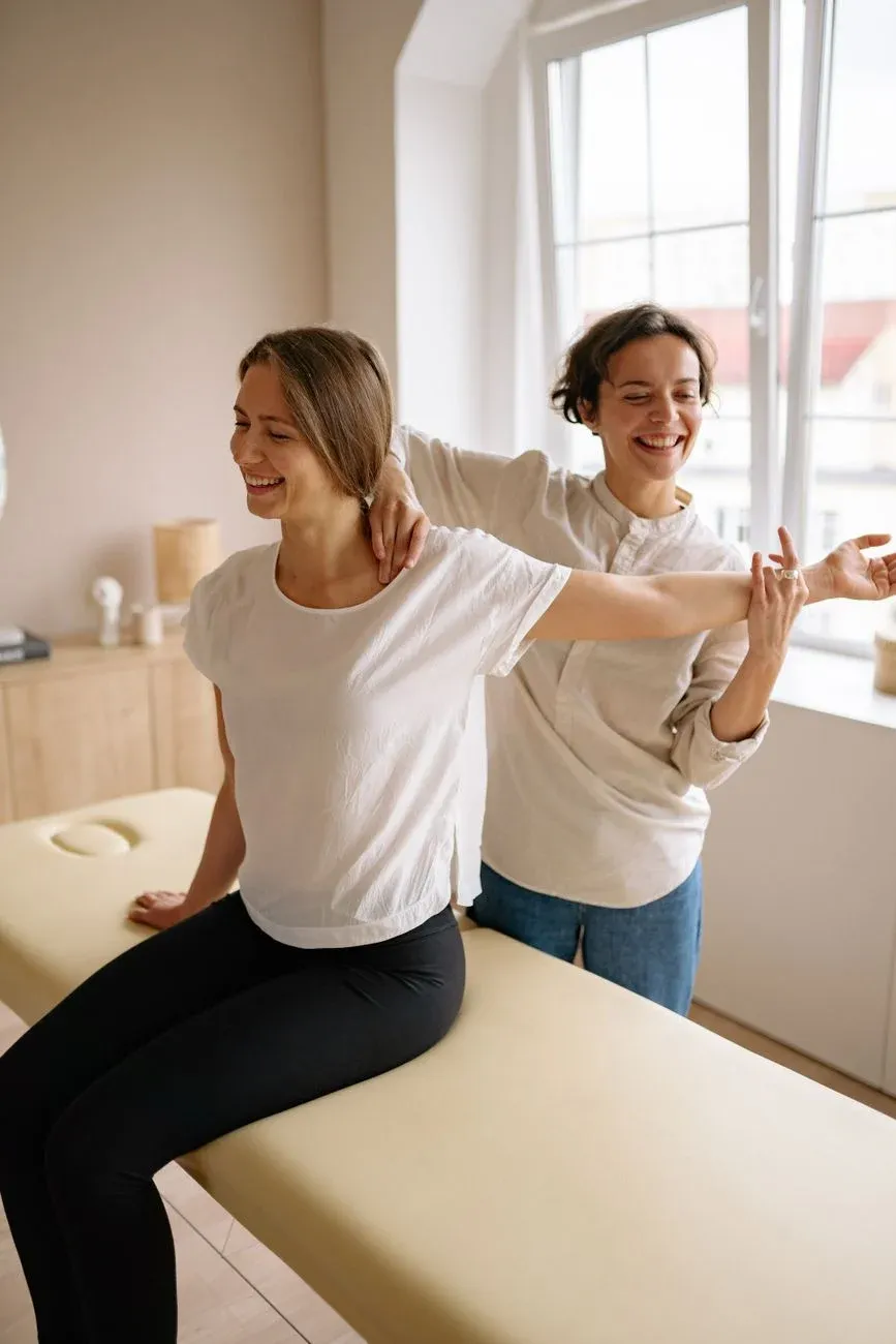 Two people performing stretching exercises by a bright window